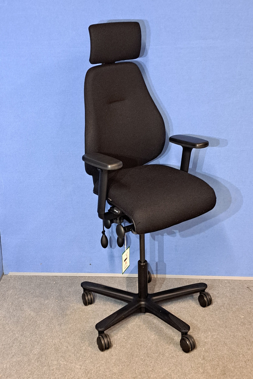 Black office chair on a blue floor with a grey wall.