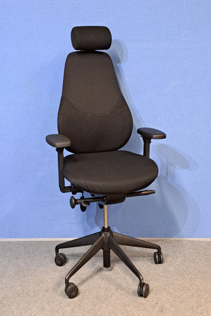 Black office chair with headrest against a blue wall