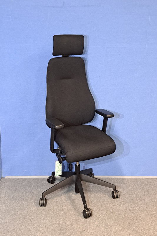 Black office chair on a blue floor with a grey wall.