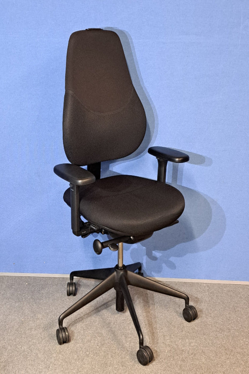 Black office chair on a grey floor with a blue wall background