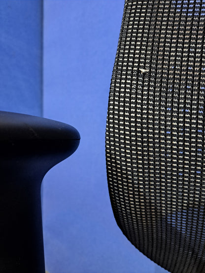 Grey mesh back office chair on a blue wall and grey carpet