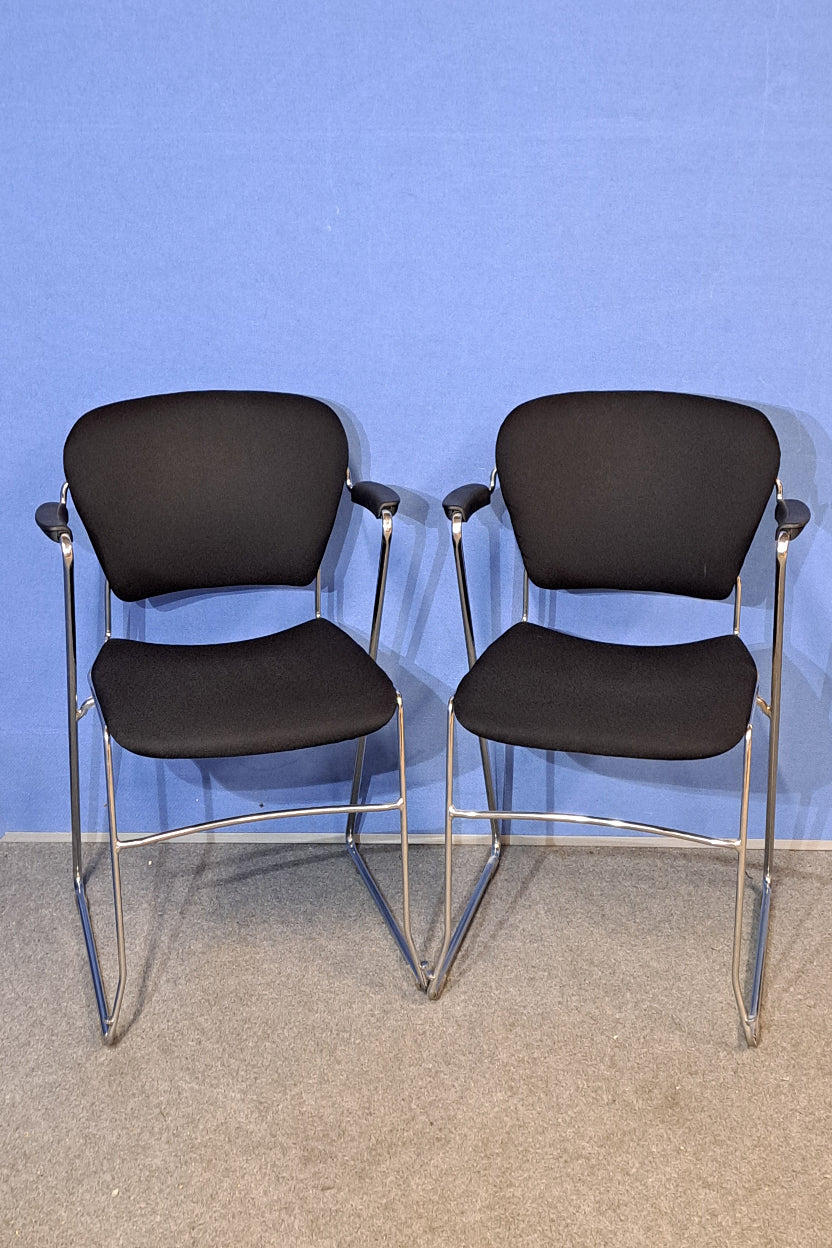 Chair with black cushioned seats against a blue wall.