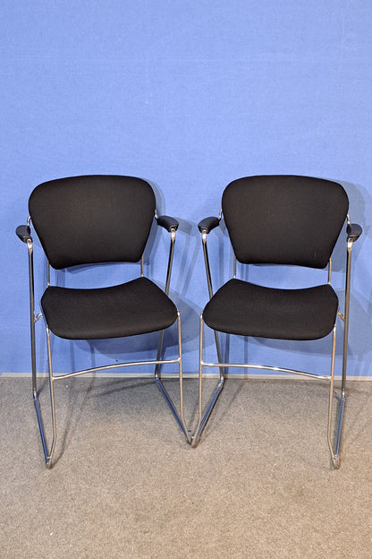 Chair with black cushioned seats against a blue wall.
