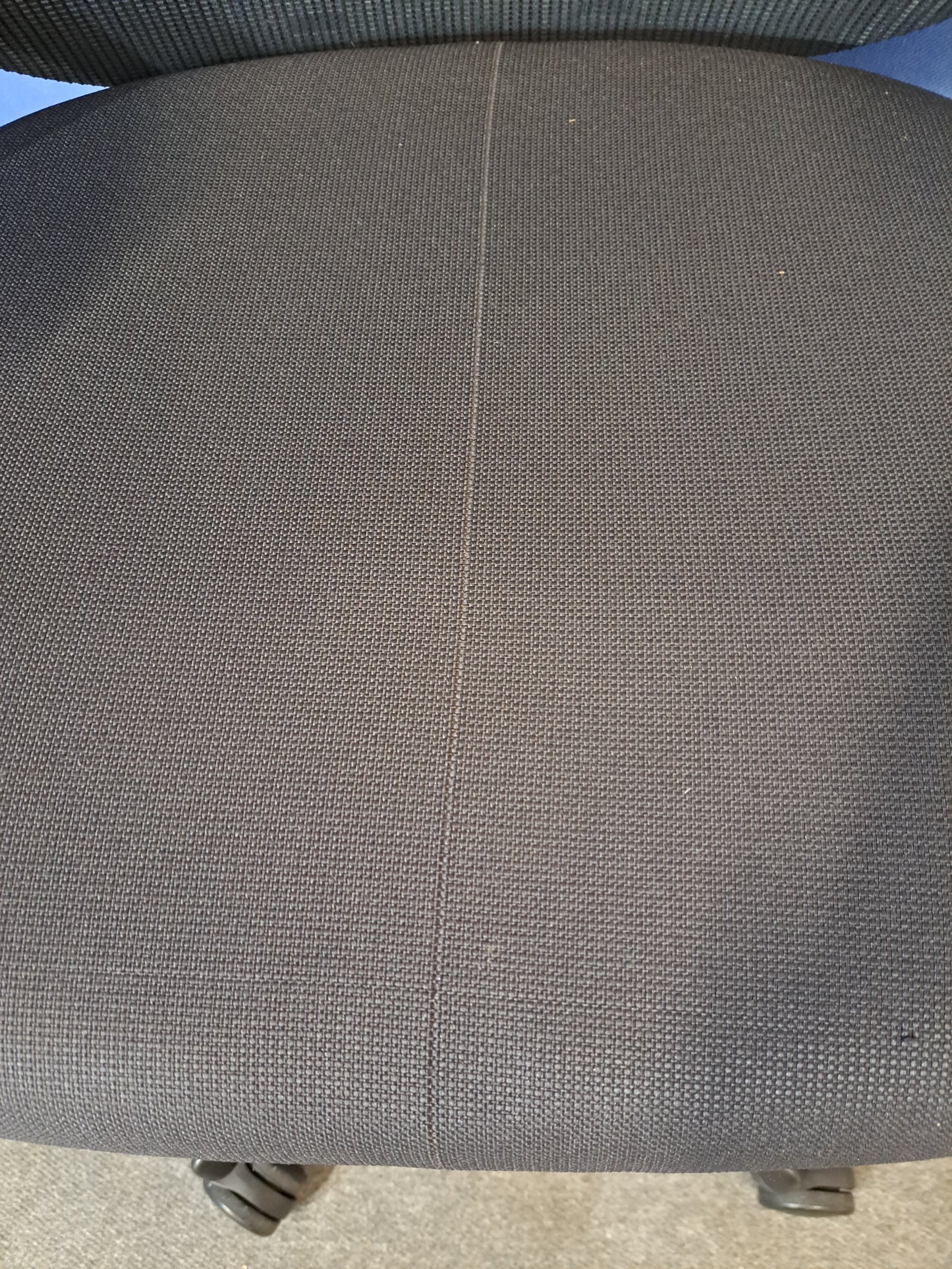 Grey mesh back office chair on a blue wall and grey carpet