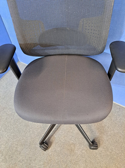 Grey mesh back office chair on a blue wall and grey carpet