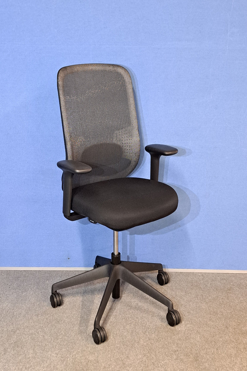 Mesh back office chair with a Grey floor and blue wall.