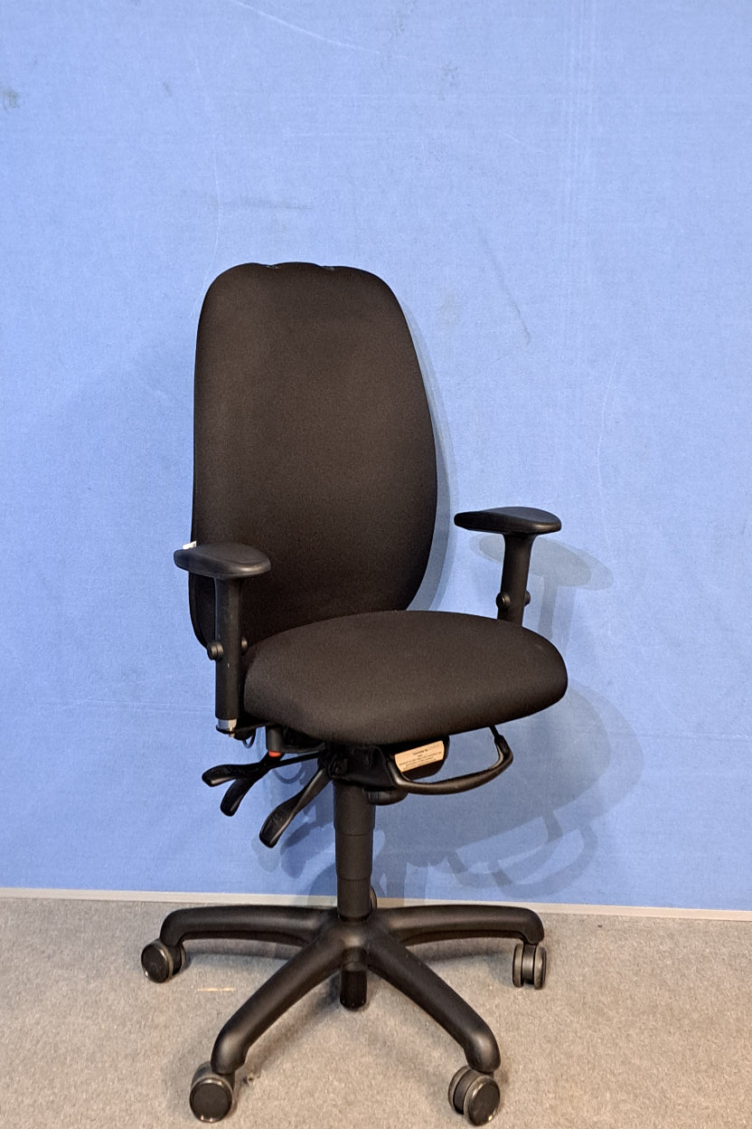 Black office chair on a grey floor with a blue wall.