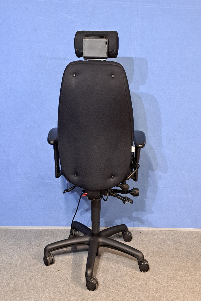 Black office chair armrest against a blue wall.