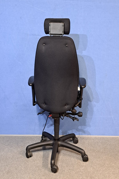 Black office chair armrest against a blue wall.