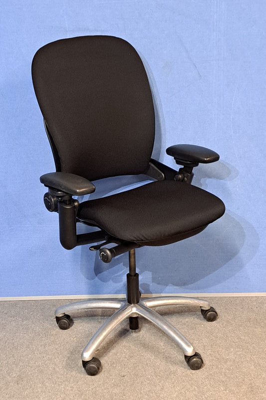 Black office chair with a chrome base against a blue wall.