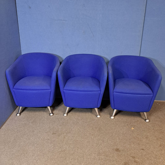 Three blue chairs with silver legs on a blue wall and grey floor