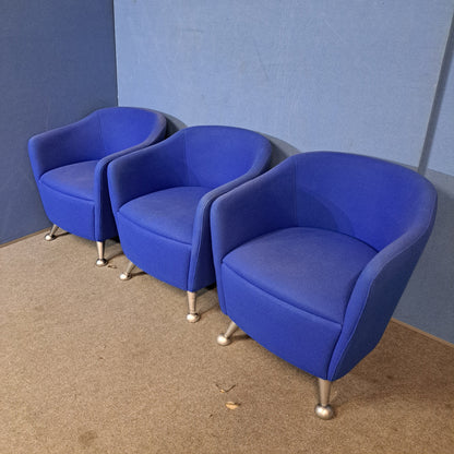 Three blue chairs with silver legs on a blue wall and grey floor