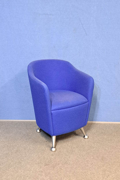 Blue chair with silver legs on a blue wall and grey floor