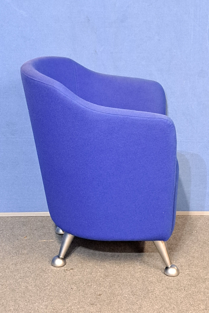 Blue chair with silver legs on a blue wall and grey floor