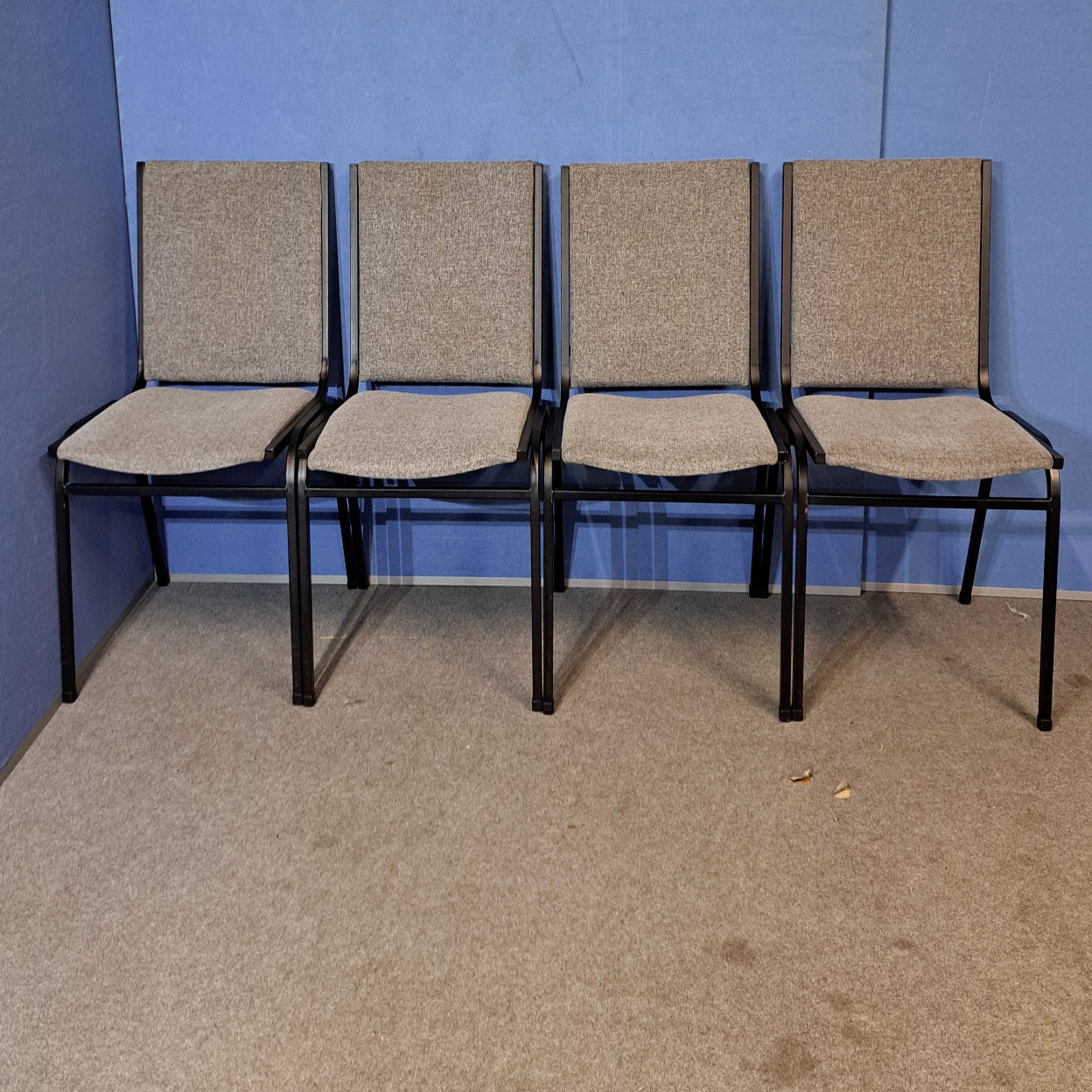 Four grey meeting chairs on a blue background and grey floor