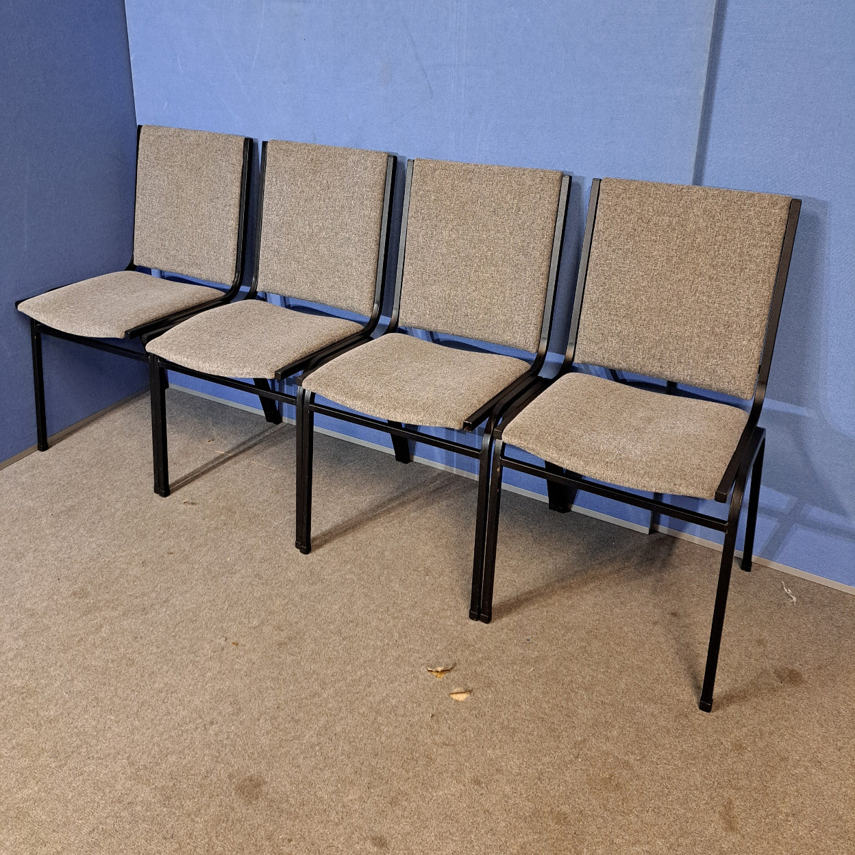 Four grey meeting chairs on a blue background and grey floor