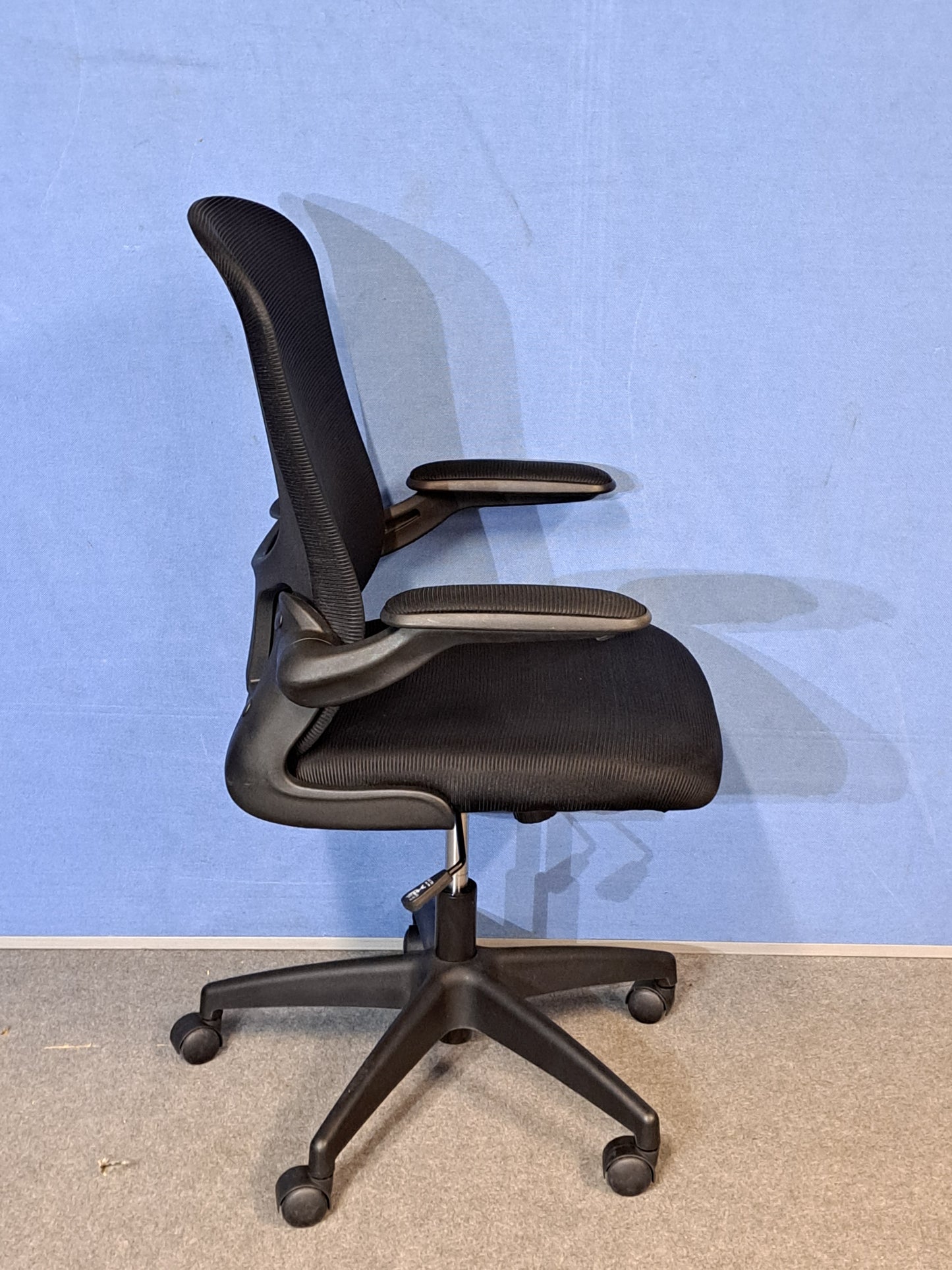 Black office chair on a blue background and grey floor