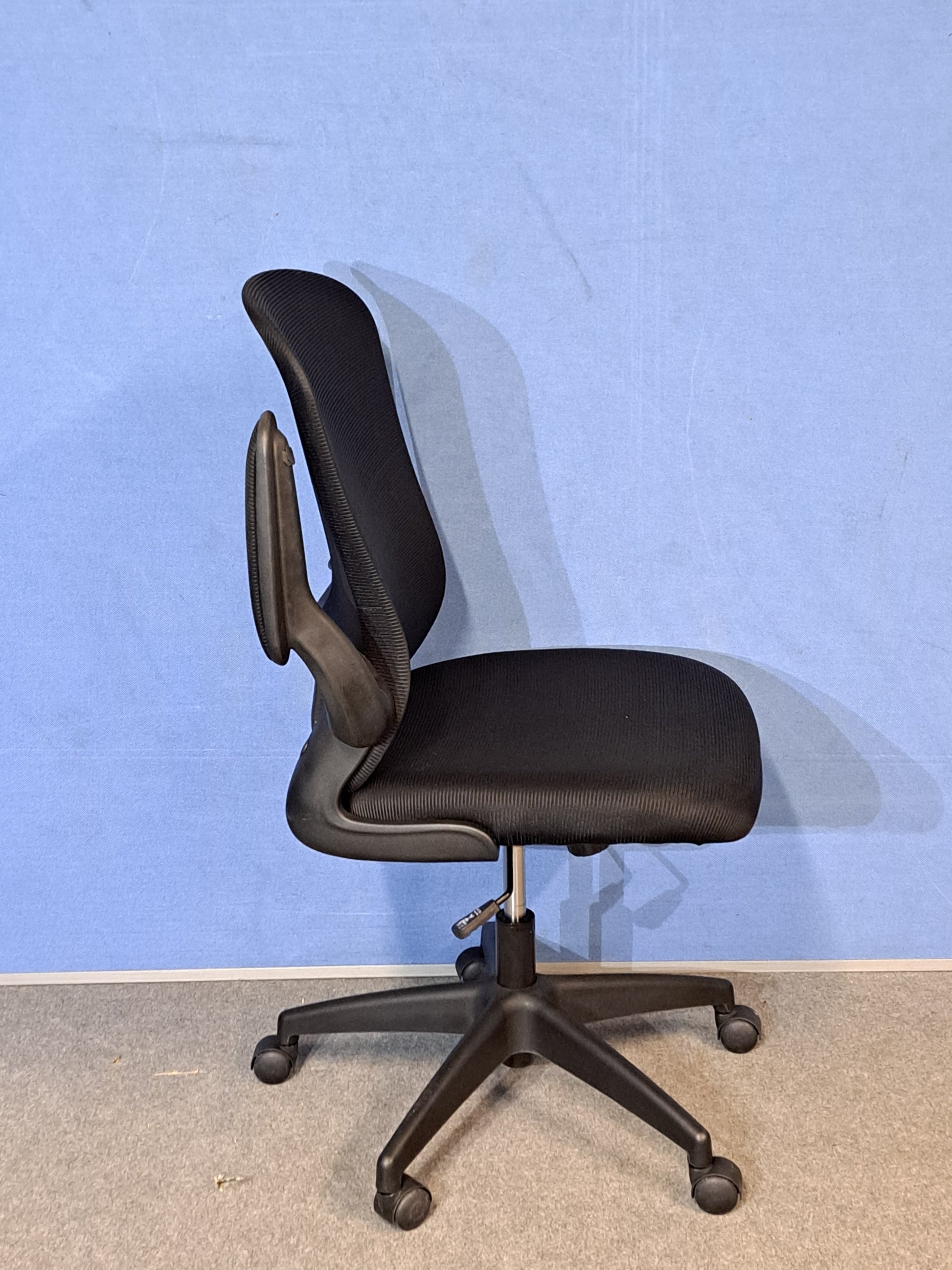 Black office chair on a blue background and grey floor