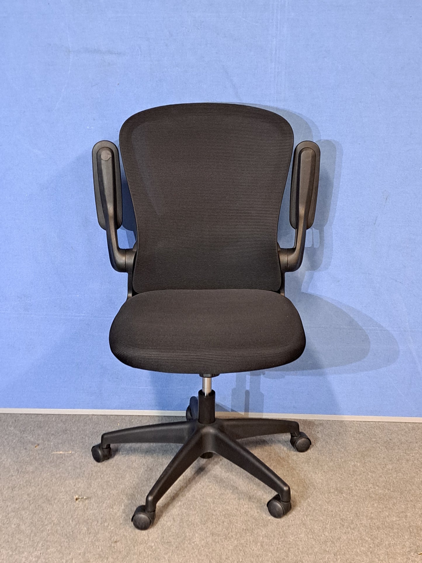 Black office chair on a blue background and grey floor