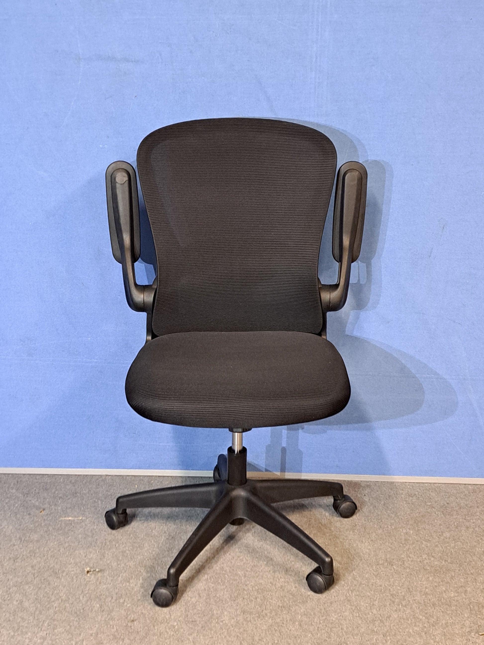 Black office chair on a blue background and grey floor