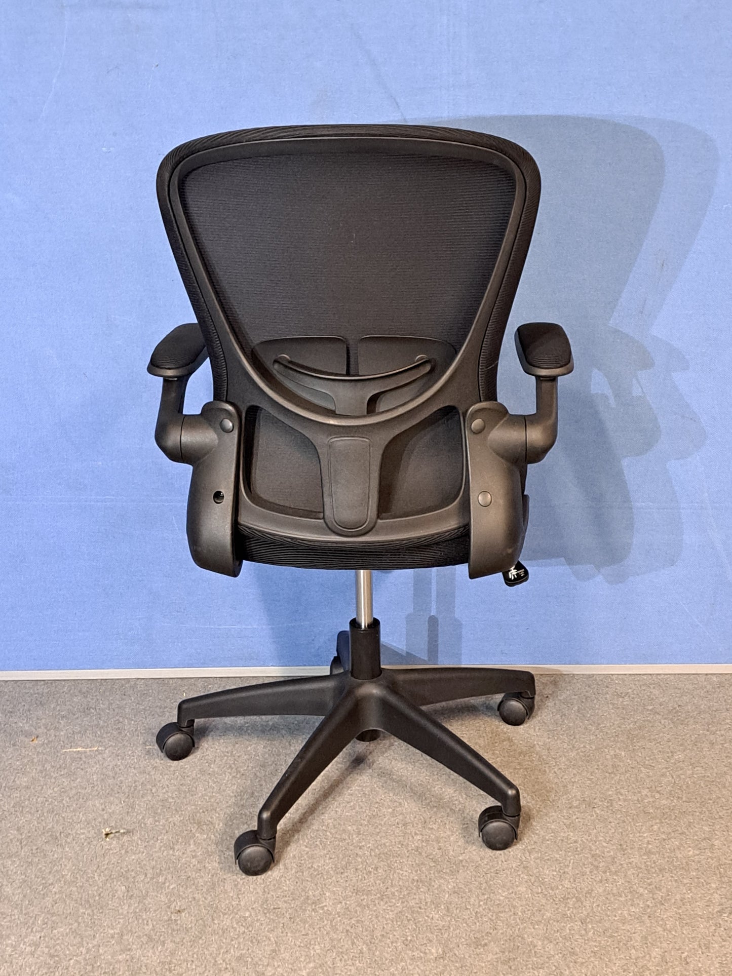 Black office chair on a blue background and grey floor