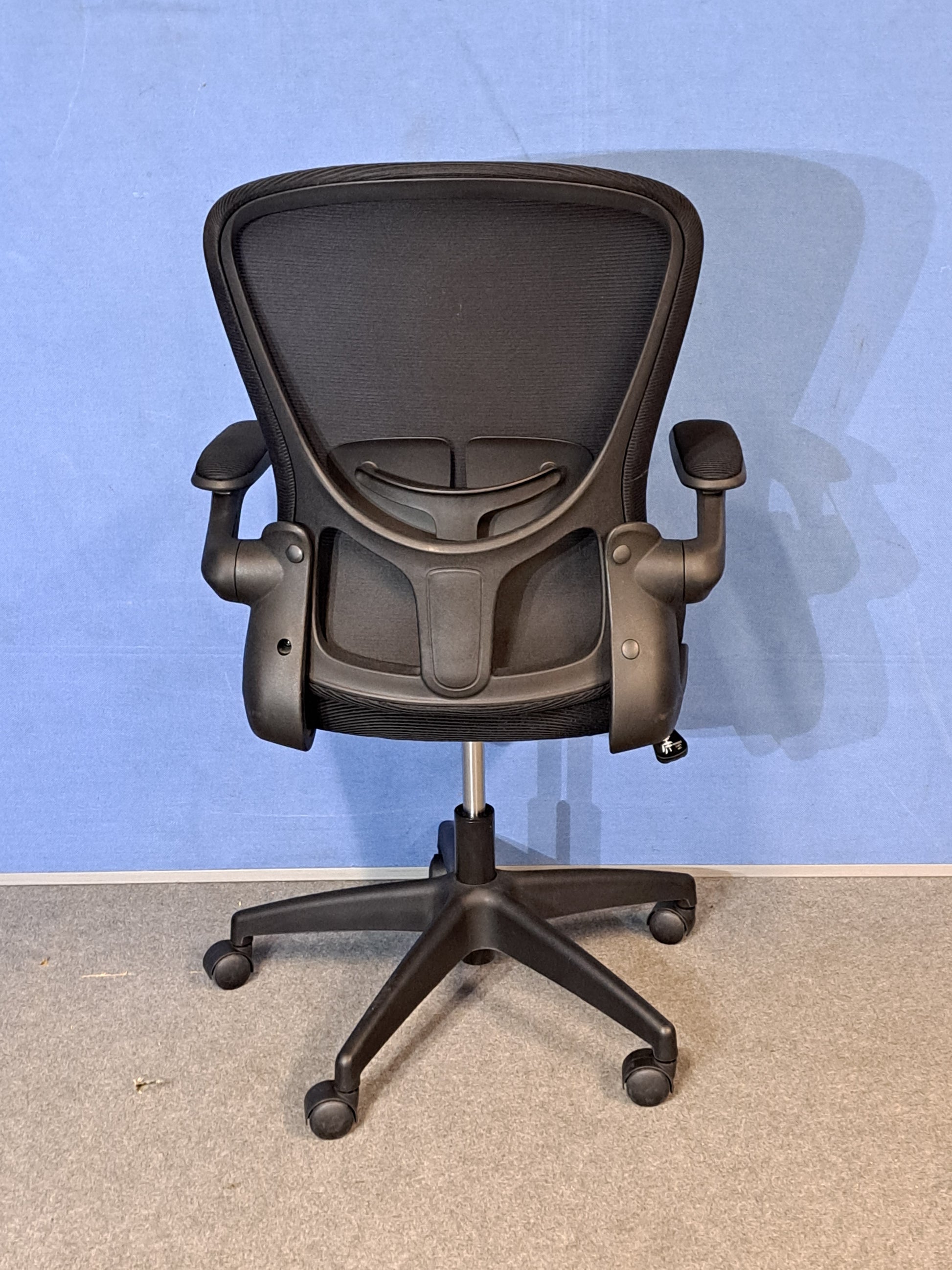 Black office chair on a blue background and grey floor