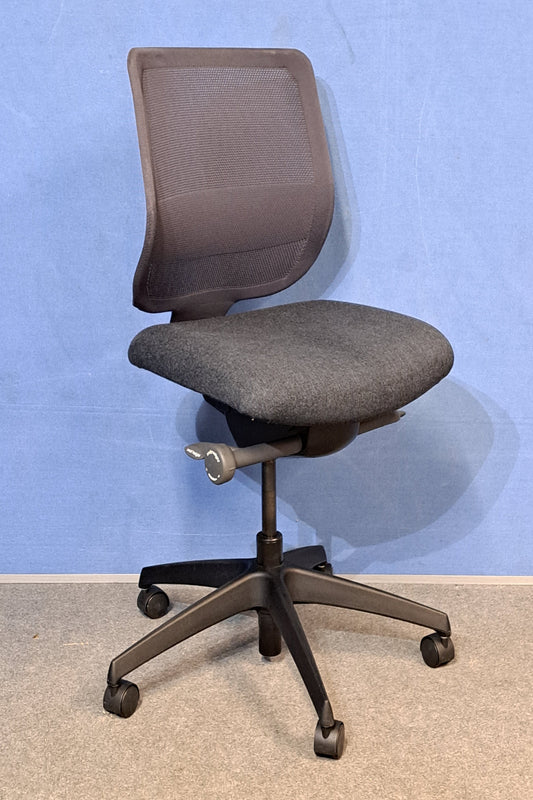 Grey office chair on a blue wall and grey carpet.