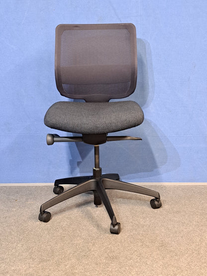 Grey office chair on a blue wall and grey carpet.