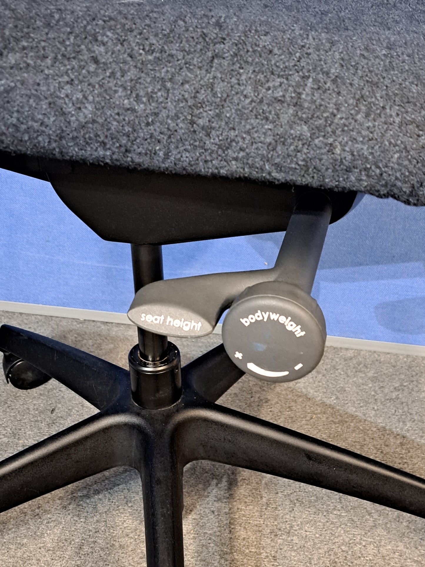 Grey office chair on a blue wall and grey carpet.