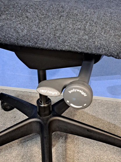 Grey office chair on a blue wall and grey carpet.