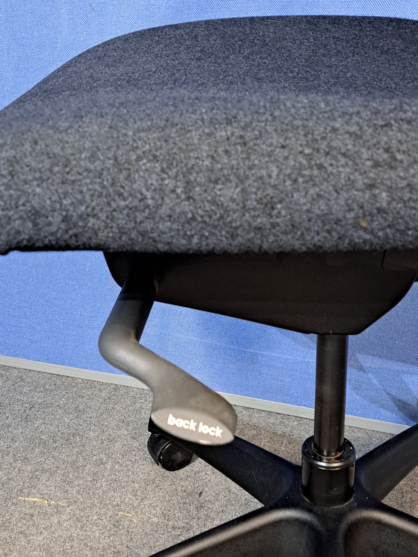Grey office chair on a blue wall and grey carpet.