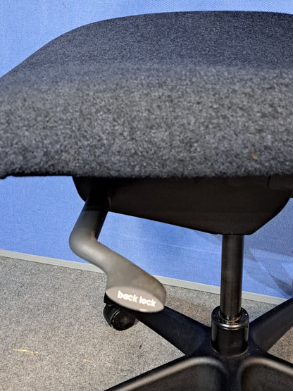 Grey office chair on a blue wall and grey carpet.