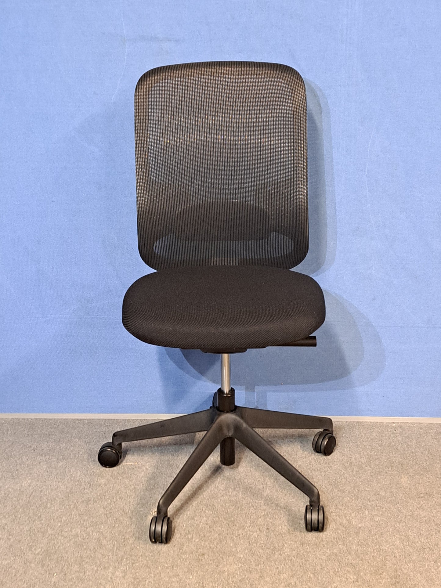 Black office chair on a blue wall and grey carpet