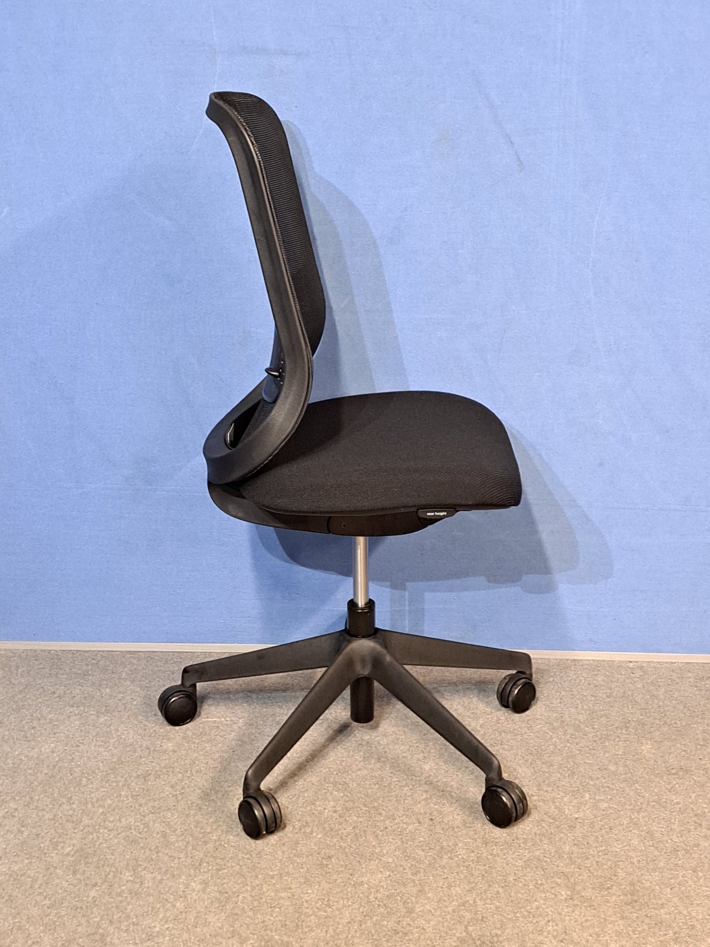 Black office chair on a blue wall and grey carpet