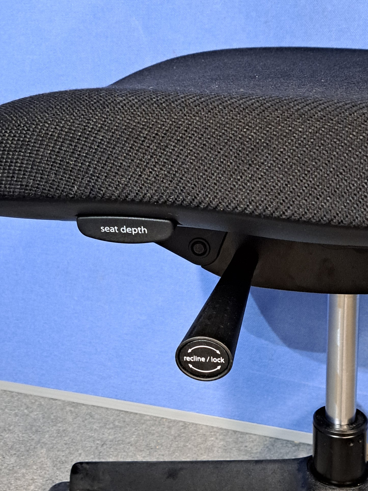 Black office chair on a blue wall and grey carpet