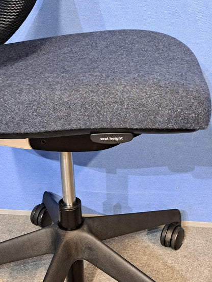Grey / black office chair on a blue wall and grey carpet