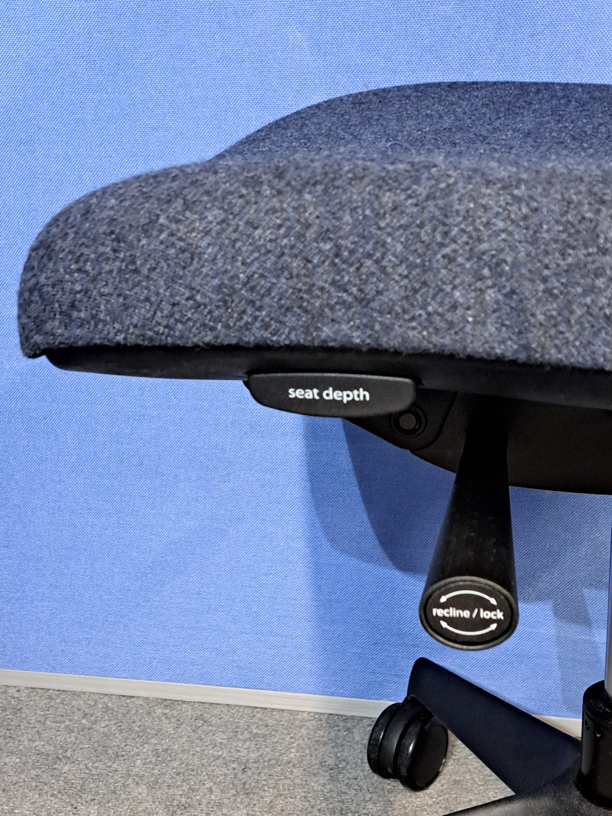 Grey / black office chair on a blue wall and grey carpet