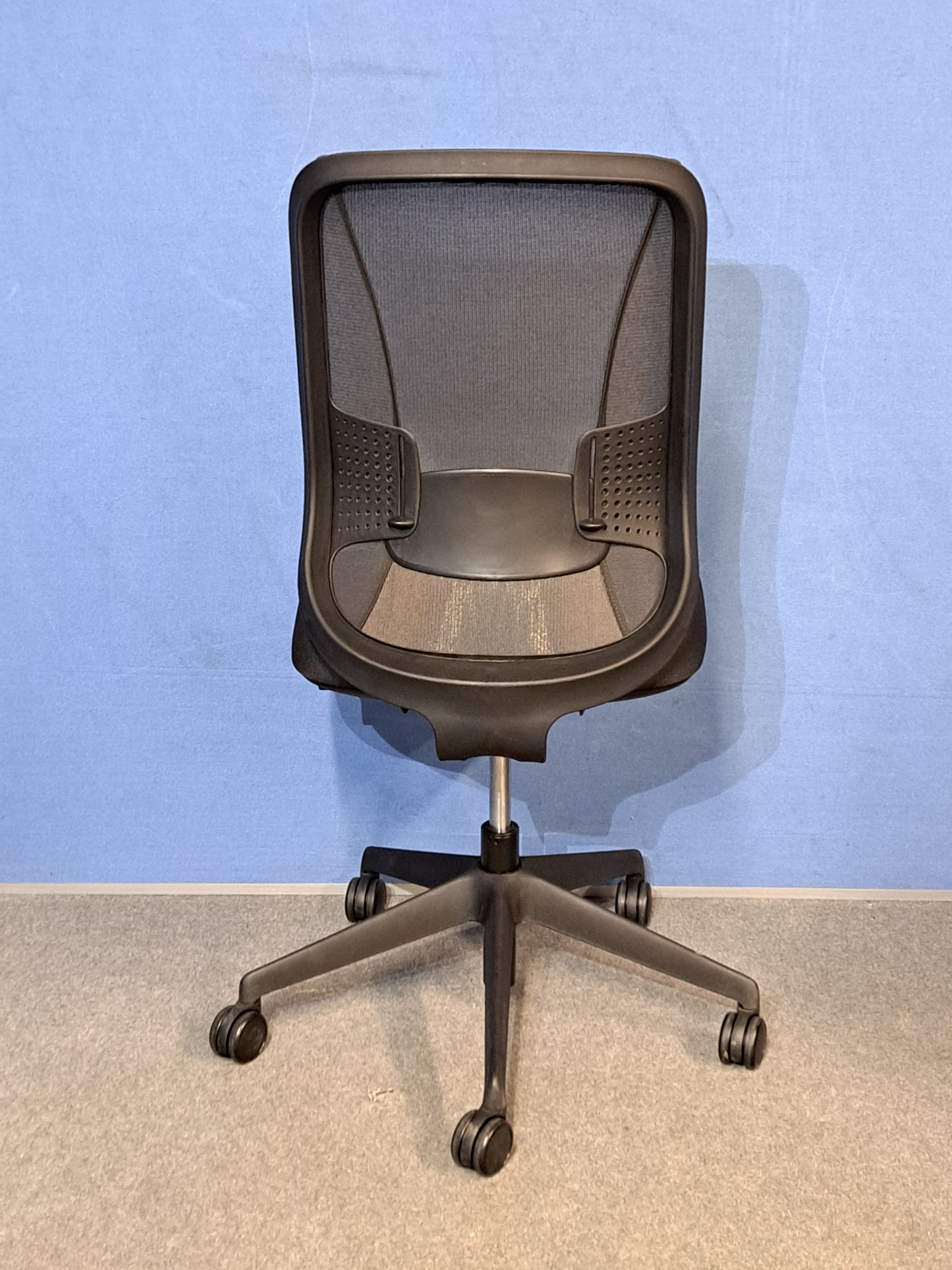 Black office chair on a blue wall and grey carpet