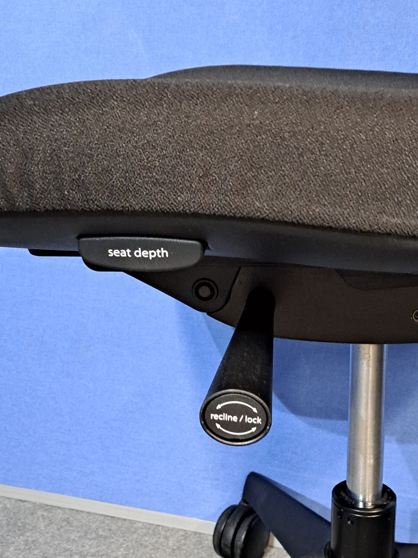 Black office chair on a blue wall and grey carpet