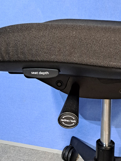 Black office chair on a blue wall and grey carpet