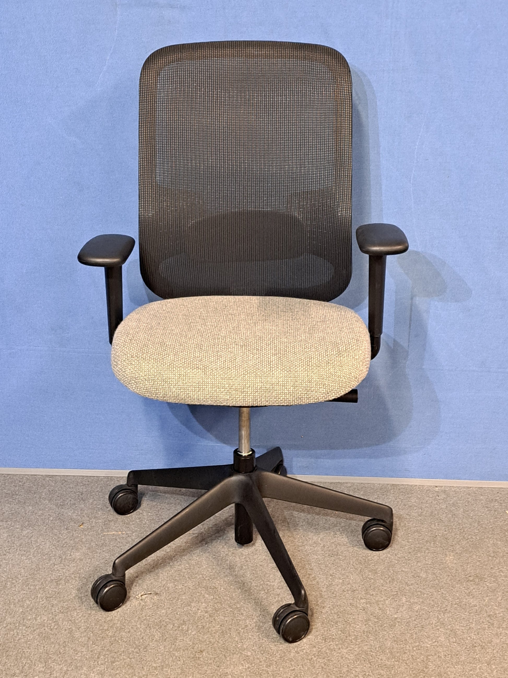 Grey office chair on a blue wall and grey carpet