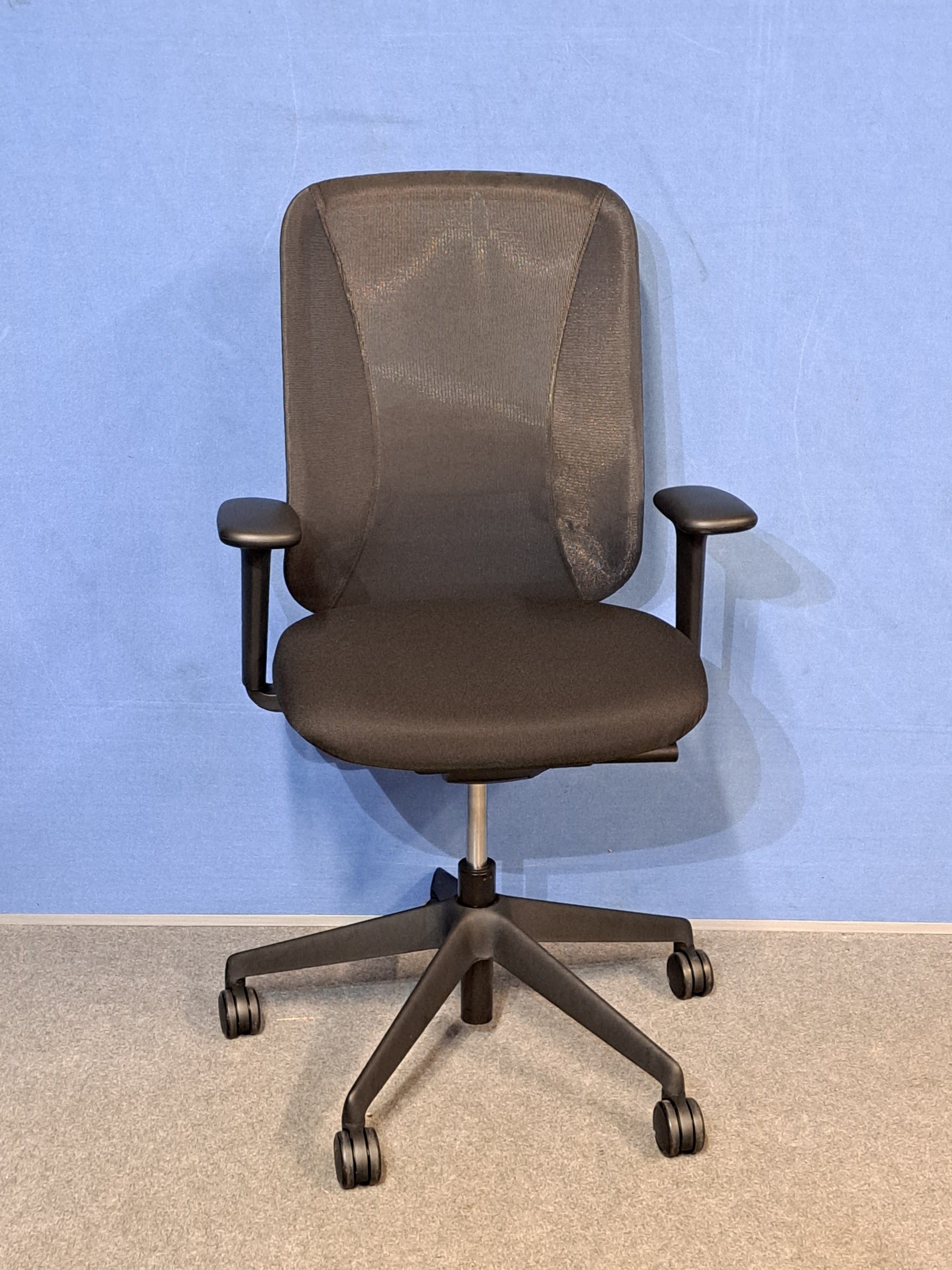Black office chair on  blue wall and grey carpet