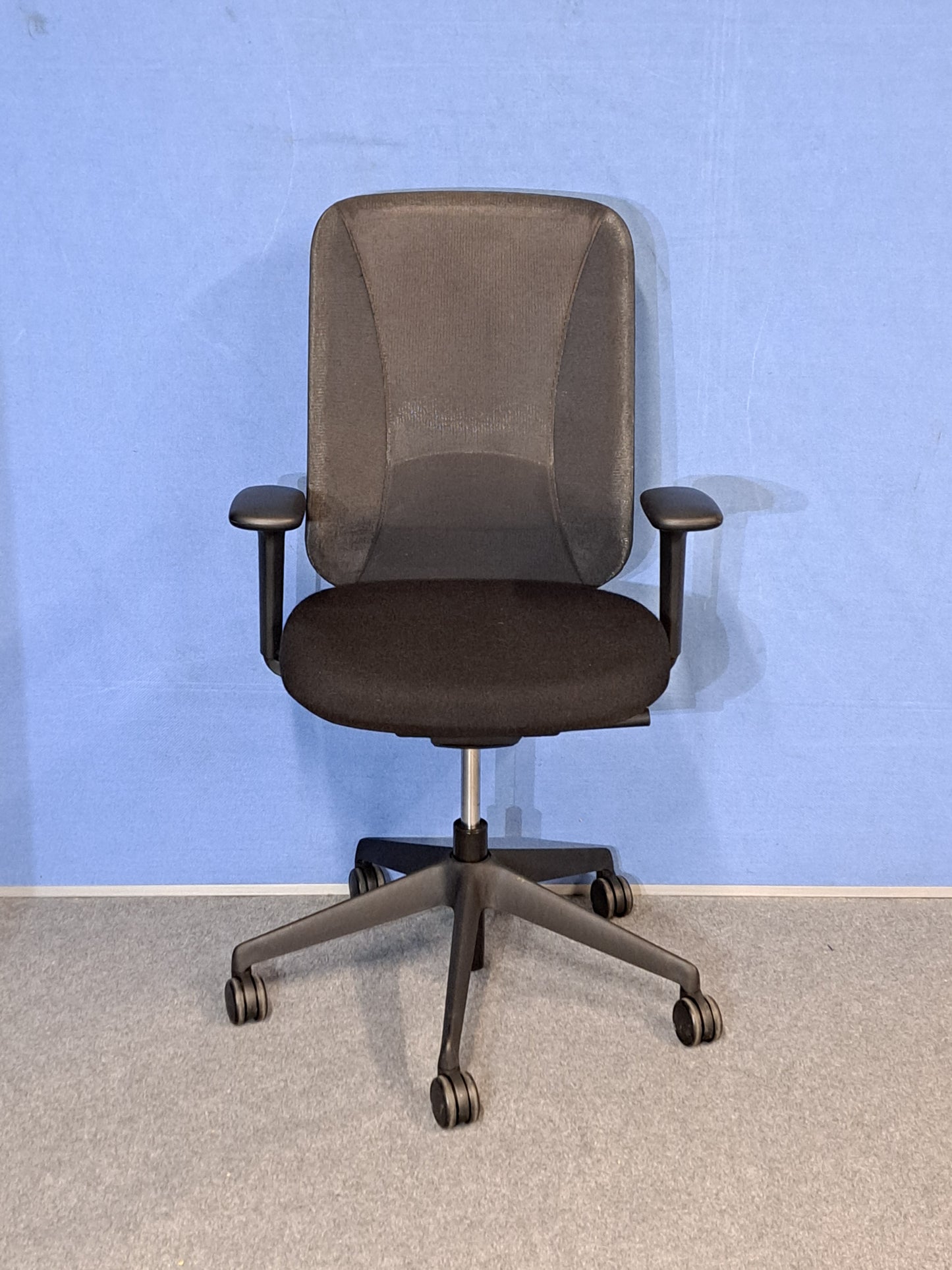 Black office chair on a blue wall and grey carpet