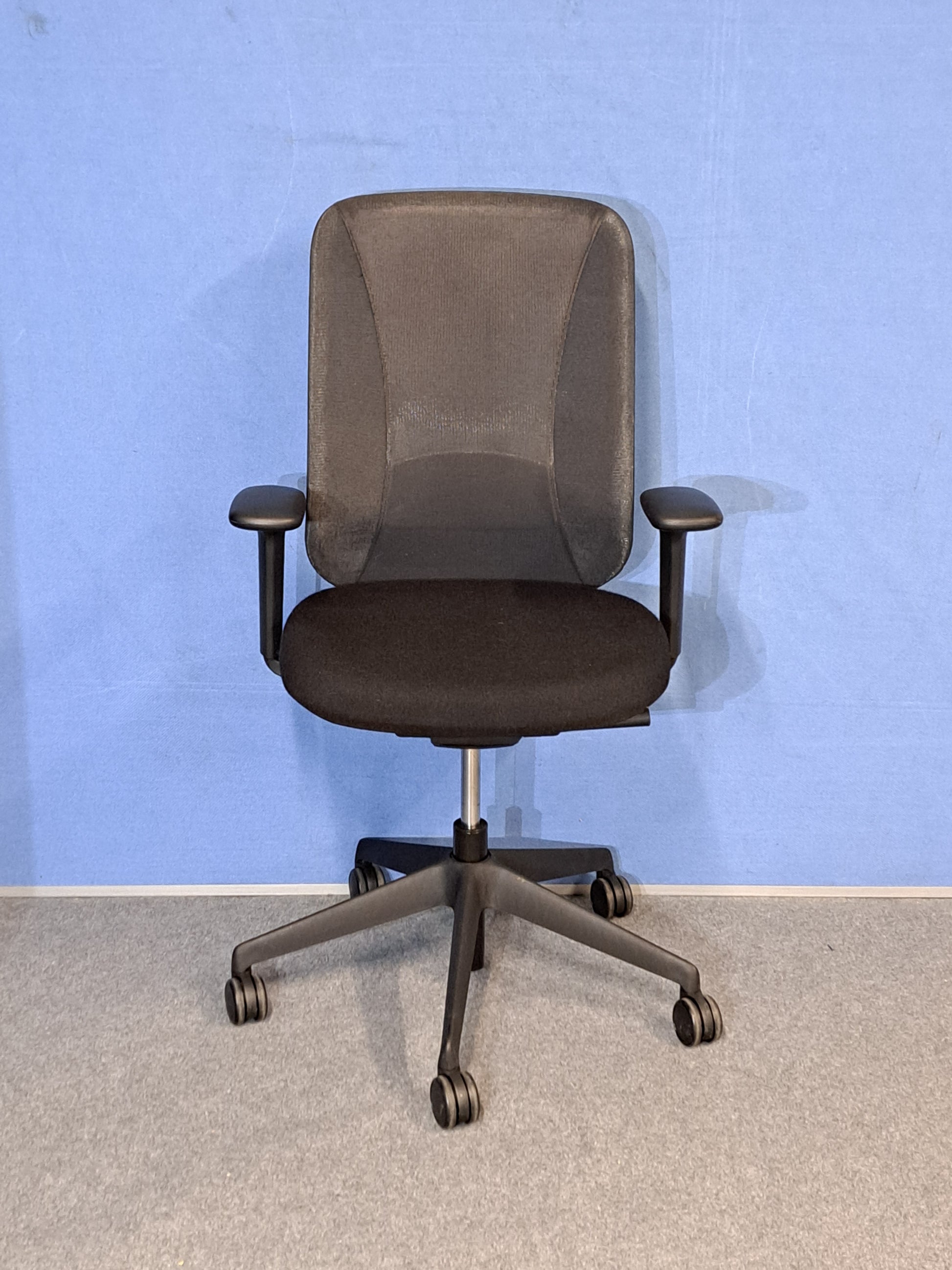 Black office chair on a blue wall and grey carpet