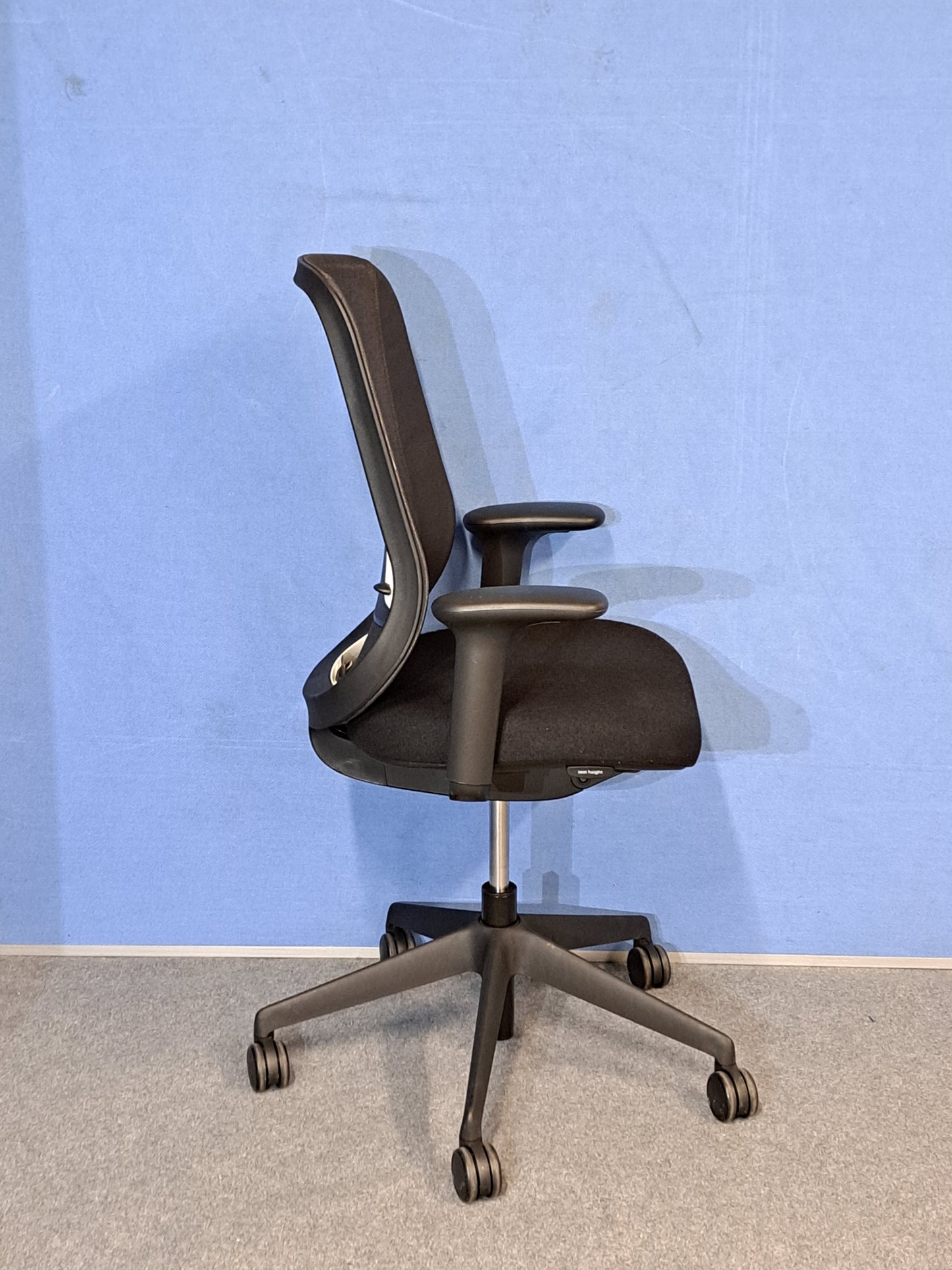 Black office chair on a blue wall and grey carpet