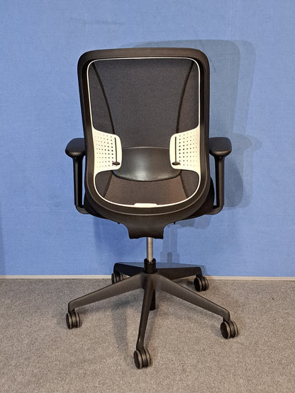 Black office chair on a blue wall and grey carpet