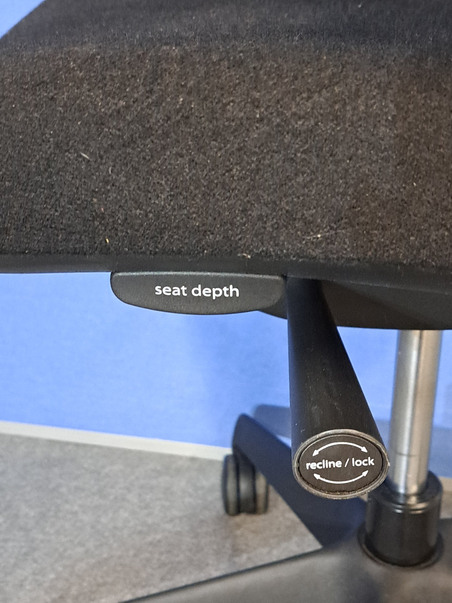 Black office chair on a blue wall and grey carpet