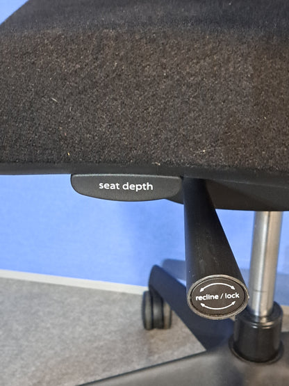 Black office chair on a blue wall and grey carpet