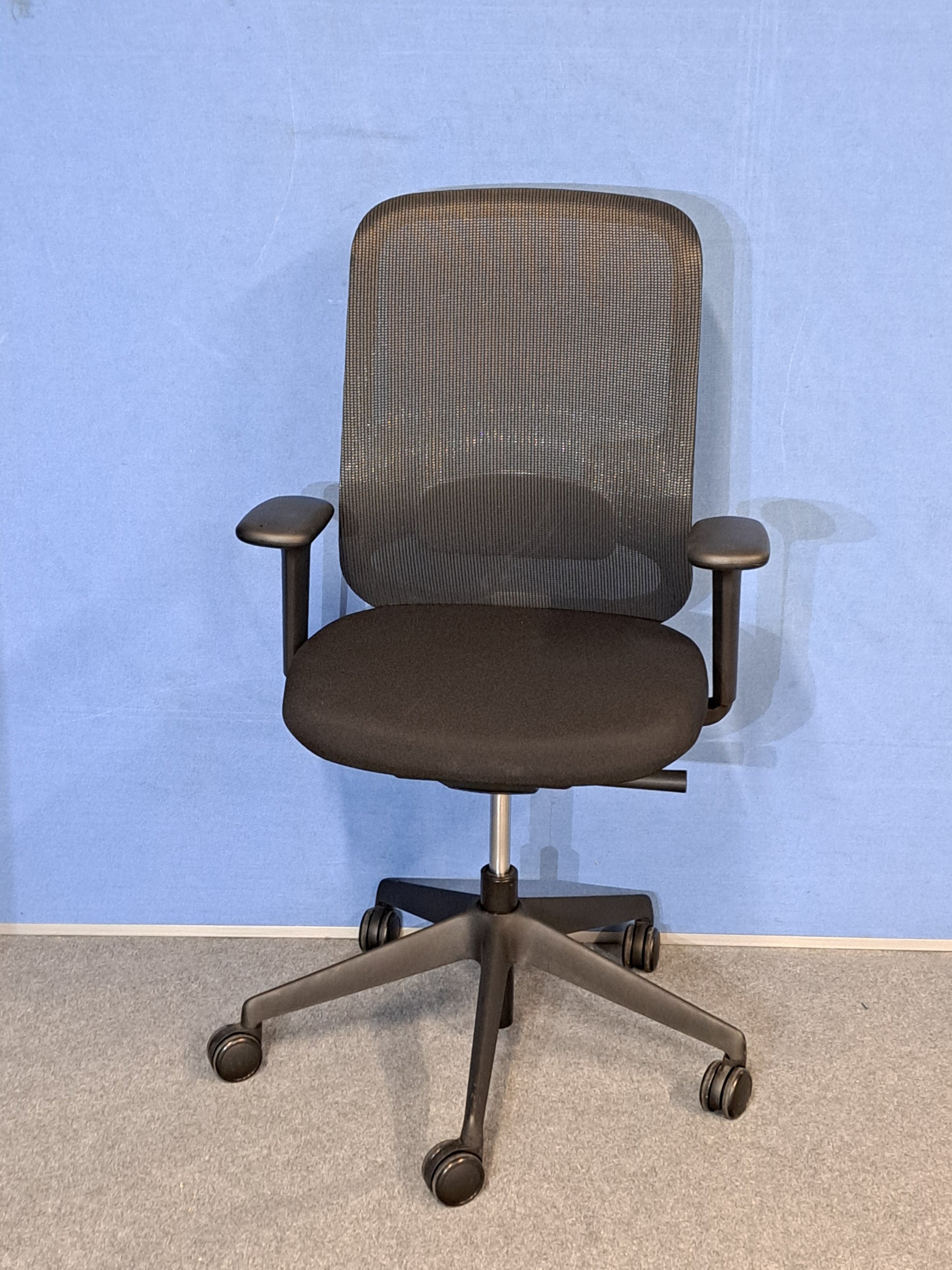 Black office chair on blue wall and grey carpet