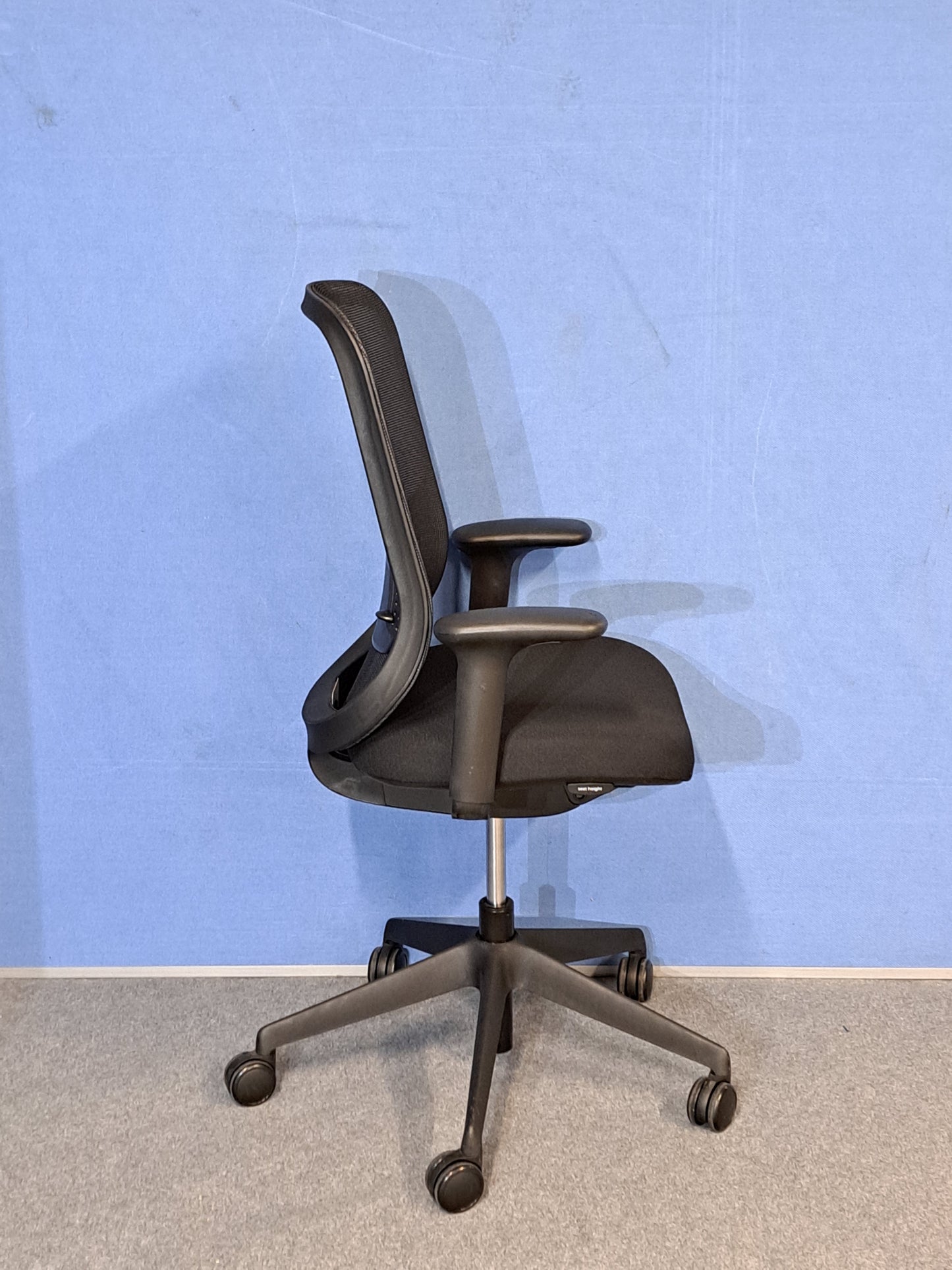 Black office chair on blue wall and grey carpet